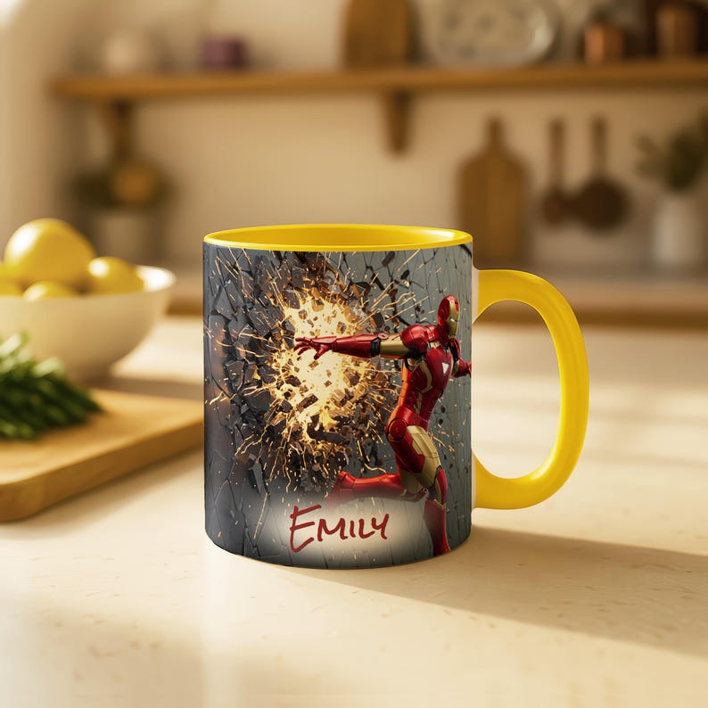 May include: Yellow-handled coffee mug featuring Iron Man breaking through a wall. The mug has a yellow interior and the name "Emily" is written on the front.