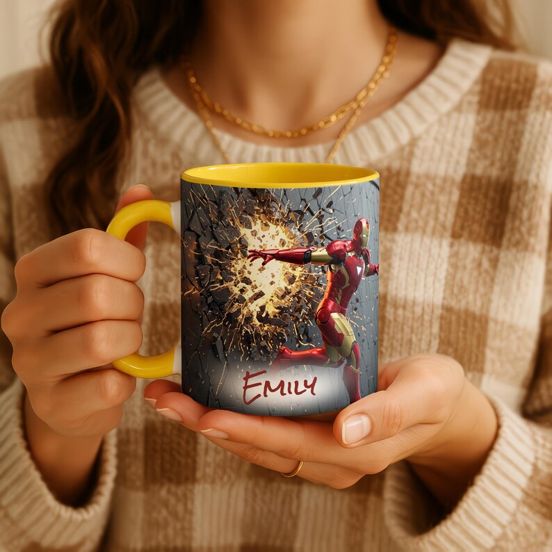 May include: A yellow-handled mug featuring Iron Man breaking through a wall. The mug's interior is yellow, and the exterior has a gray background with a red and gold Iron Man graphic. The name "Emily" is written in red script.