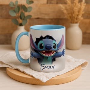 Puede incluir: Una taza de cer&aacute;mica blanca con interior y asa azules. La taza presenta una imagen 3D del personaje Stitch rompiendo una pared. El nombre "Emily" est&aacute; escrito en cursiva debajo de la imagen.