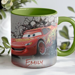 May include: A ceramic mug featuring a red race car design with the name "Emily" in red script. The mug has a green handle and interior, with a background of a cracked wall. The mug is a fun item for fans of the animated movie.