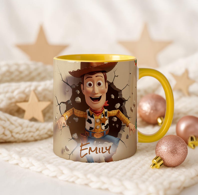 May include: A ceramic mug with a yellow handle and interior, featuring Woody from Toy Story bursting through a wall. The mug has the name "Emily" printed on it. The background includes decorative stars and baubles, creating a festive theme.