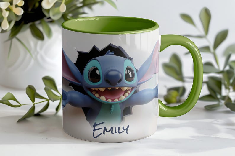 Puede incluir: Taza de cer&aacute;mica blanca con asa e interior verdes. La taza presenta un personaje de dibujos animados rompiendo una pared, con el nombre "Emily" escrito debajo. El personaje es azul con ojos grandes y una amplia sonrisa.