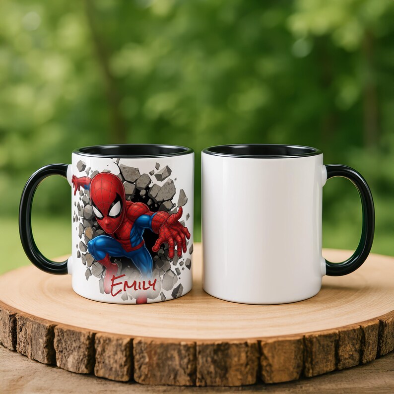 K&ouml;nnte beinhalten: Zwei wei&szlig;e Keramikbecher mit schwarzen Griffen und R&auml;ndern. Ein Becher zeigt eine farbenfrohe Spider-Man-Grafik mit dem Namen "Emily" und einem Design mit Rissen in der Wand. Der andere Becher ist schlicht wei&szlig;.