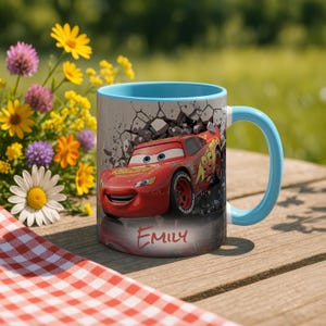 May include: A ceramic mug with a light blue handle and interior. The mug features a red race car design with the name "Emily" printed on the front. The background includes a cracked wall effect.