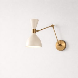 May include: Cream-colored wall sconce with a brass finish. The sconce features a conical shade and a pivoting arm, attached to a round wall plate. The design is a blend of modern and vintage styles, suitable for interior lighting.