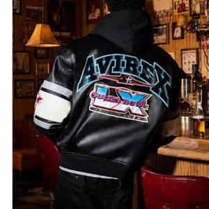Peut inclure: Veste en cuir noire avec le mot "AVIREX" en lettres bleues et blanches dans le dos. La veste comporte &eacute;galement un &eacute;cusson "Super Bowl IX". Les manches ont des rayures blanches et noires avec une &eacute;toile rouge.