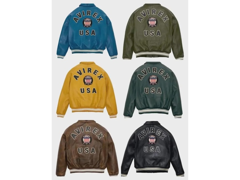 May include: Six leather bomber jackets in shades of blue, olive green, mustard, dark green, brown, and black. Each jacket displays the "AVIREX USA" logo on the back, with a crest. The jackets have ribbed cuffs and waistbands. The jackets are a classic style.