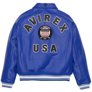 May include: A vibrant blue leather jacket with the word "AVIREX" arched across the shoulders in black and white lettering. The back of the jacket features a patch with the American flag and the words "ALL AMERICANS" and "USA". The jacket has white and blue striped cuffs.