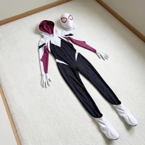 May include: A black, white, and maroon Spider-Gwen costume set. The set includes a hooded jumpsuit, gloves, and a mask. The jumpsuit is primarily black with white accents and maroon patterned sleeves.