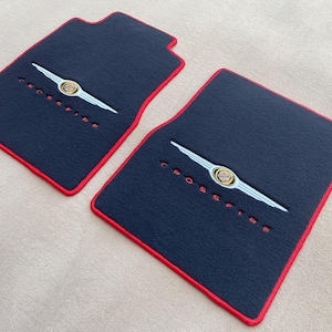 Op de afbeelding: Een witte keramische mok met een zwarte handgreep en de tekst "But First, Coffee" in handschriftstijl. De mok staat op een wit oppervlak. De mok is 10 cm hoog.