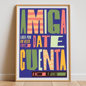 May include: A framed poster with a blue background and colorful text. The words "AMIGA DATE CUENTA" are prominently displayed in various colors and fonts. Additional text includes "LOCA POR UN BESO TUYO" and "O NO, Y JODETE".