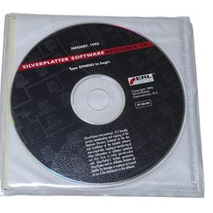 Op de afbeelding: Een cd-rom in een doorzichtige plastic hoes. De schijf is zwart met witte tekst met de tekst "SILVERPLATTER SOFTWARE RESOURCE CD" en "JANUARY, 1995". De tekst "Type SPMENU to begin" is ook zichtbaar. De schijf heeft een zilveren midden en het ERL Compliant logo.