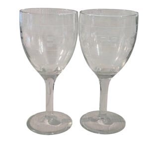 Puede incluir: Dos copas de vino transparentes con patrones horizontales y cuadrados grabados. Las copas tienen un diseño clásico con un cuenco redondeado, un tallo delgado y una base circular. La cristalería es ideal para servir vino.