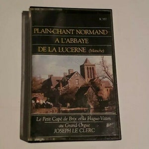 May include: A cassette tape case with a black and white photo of a church and the text "PLAIN-CHANT NORMAND A L'ABBAYE DE LA LUCERNE (Manche)" and "Le Petit Capé de Brix et la Hague-Vaten au Grand Orgue JOSEPH LE CLERC".
