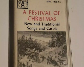 Op de afbeelding: Een cassettebandje met een zwart-witte illustratie van een besneeuwde winterscène met mensen die over een pad lopen. De tekst op de cassettebandje luidt "A Festival of Christmas, New and Traditional Songs and Carols, Cassette No. 2".