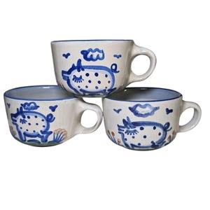 Puede incluir: Un juego de tres tazas de cerámica con un acabado moteado y mate. Las tazas son de color crema, gris claro y gris oscuro. Cada taza tiene un diseño simple y minimalista, ideal para café o té.