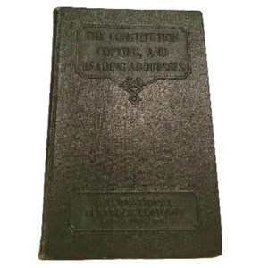 Könnte beinhalten: Ein dunkelgrünes Buch mit dem Titel "The Constitution, Copies and Reading Addresses" auf dem vorderen Einband. Das Buch wurde von der International Textbook Company herausgegeben.