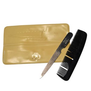 May include: A vintage manicure set featuring a black comb, a metal nail file with the text "Triple Cut Made U.S.A.", and a yellow case with a decorative emblem. The set is designed for nail care.
