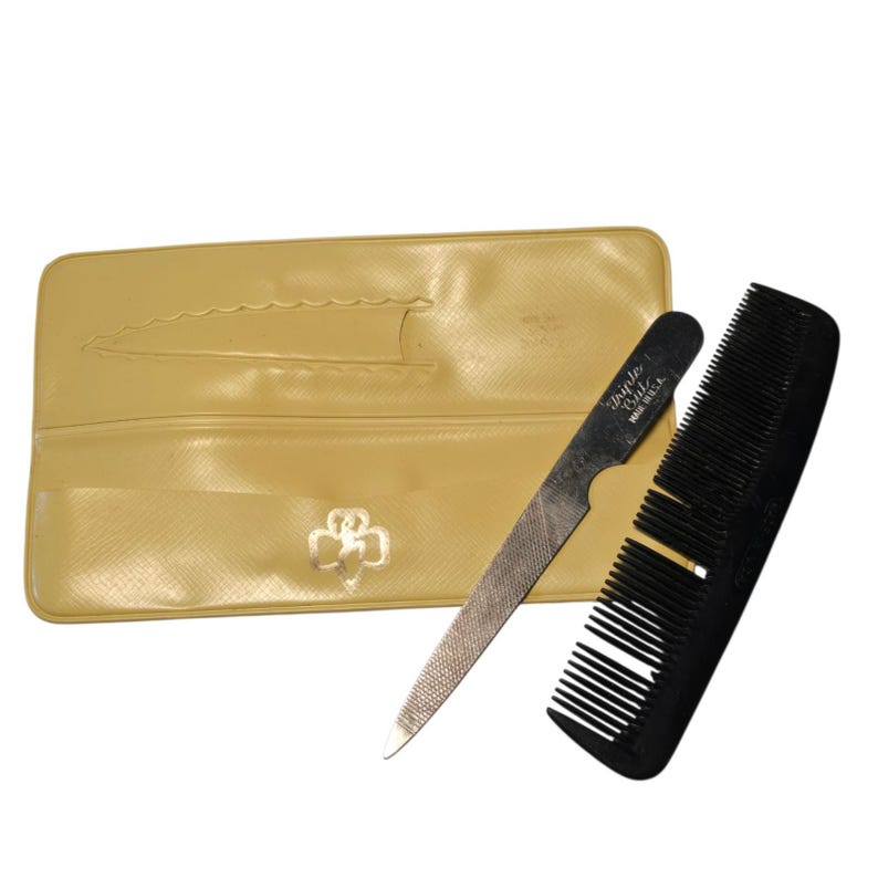 May include: A vintage manicure set featuring a black comb, a metal nail file with the text "Triple Cut Made U.S.A.", and a yellow case with a decorative emblem. The set is designed for nail care.