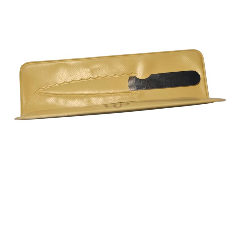 May include: A tan-colored knife sheath with a black knife blade partially visible. The sheath has a textured surface and a scalloped edge. The knife is designed to fit snugly within the sheath.