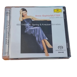 May include: A Super Audio CD case featuring Anne-Sophie Mutter in a blue satin strapless dress. The cover text reads: Anne-Sophie MUTTER, Lambert ORKIS, piano, BEETHOVEN, Spring & Kreutzer Sonatas. The Deutsche Grammophon logo is in the top right corner.