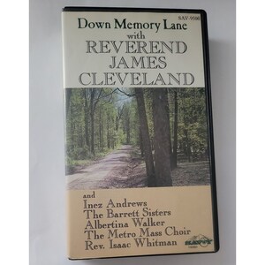 May include: A VHS video cassette with a black and white image of a forest path. The title is "Down Memory Lane" with "Reverend James Cleveland" in large letters. The text "SAV-9500" is in the upper right corner. The text "with" is below the title. The text "and" is in the lower left corner, followed by a list of names: "Inez Andrews, The Barrett Sisters, Albertina Walker, The Metro Mass Choir, Rev. Isaac Whitman". The text "VIDEO" is in the lower right corner.