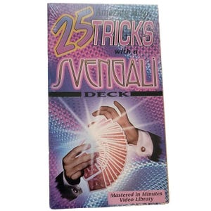 Op de afbeelding: Een paarse en blauwe VHS-tape met een zilveren stervormig ontwerp. De tape heeft de titel "25 Tricks with a Svengali Deck" en toont de handen van een goochelaar die een kaartspel vasthouden. De tekst "Mastered in Minutes Video Library" staat onderaan de tape.