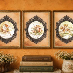 May include: Three rectangular wall art prints featuring illustrations of a frog character in various fishing scenes. Each print is enclosed in an ornate, dark, oval-shaped frame set against a warm, light-brown, textured background.