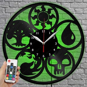 May include: A circular wall clock crafted from a black vinyl record, featuring five cut-out symbols representing a sun, water drop, tree, flame, and skull. The clock face is black with white numbers and silver hands. A remote control is included.