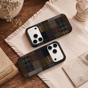 Puede incluir: Dos fundas rectangulares para smartphone con un diseño de patchwork de varios patrones de cuadros y tartán en tonos oscuros como verde bosque, azul marino, burdeos, marrón y gris, con un módulo de cámara blanco con tres lentes circulares.