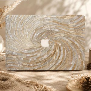 Può includere: Una cover rettangolare per laptop caratterizzata da un motivo a mosaico vorticoso composto da tessere iridescenti, color crema e beige, simili a conchiglie. Il design si irradia da un ritaglio centrale a forma di logo Apple, creando una superficie testurizzata e scintillante.