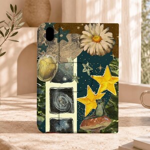 Puede incluir: Una funda para tableta con un diseño de collage que presenta una margarita blanca, un escarabajo dorado, una pequeña rana sentada sobre una seta y dos estrellas amarillas. El fondo incluye secciones azul oscuro con estrellas, una luna y una galaxia.