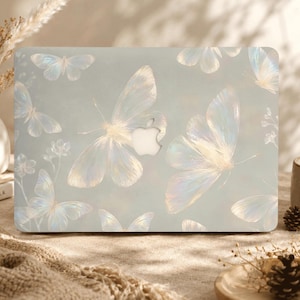 May include: A laptop hard shell case featuring a soft, pale blue background with a repeating pattern of iridescent, translucent butterflies and small floral sprigs. The center of the case displays a cutout for the Apple logo.