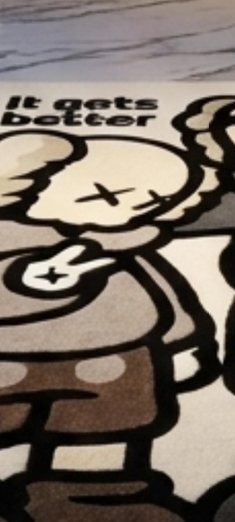 May include: A rectangular rug featuring a cartoon character with X-shaped eyes and a peace sign hand gesture. The character is rendered in shades of beige, gray, and black. The text "It gets better" is printed in bold black letters at the top.