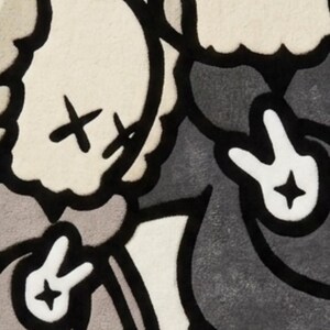 May include: A tufted rug featuring two cartoon-style figures with X-shaped eyes, wearing hoodies and making peace signs with their hands. The figures are rendered in shades of beige, gray, and black, with the partial text "gets etter" visible.