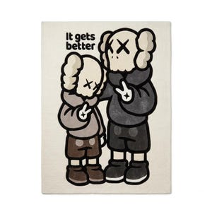 May include: A rectangular off-white throw blanket featuring a graphic illustration of two cartoon figures with X-shaped eyes. The larger figure wears a dark gray hoodie and shorts, while the smaller wears a light gray hoodie. Text reads: It gets better.