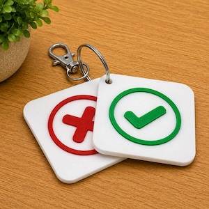 May include: Two square white keychains attached to a silver metal ring and lobster clasp. One keychain features a red embossed X symbol inside a circle, while the other displays a green embossed checkmark symbol inside a circle on a white base.