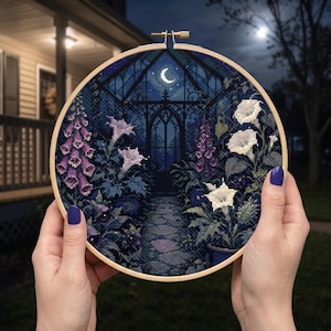 May include: A circular wooden embroidery hoop containing a cross-stitch pattern of a moonlit garden at night. The design features a stone path leading to a dark arched structure under a crescent moon, surrounded by purple foxgloves and white flowers.