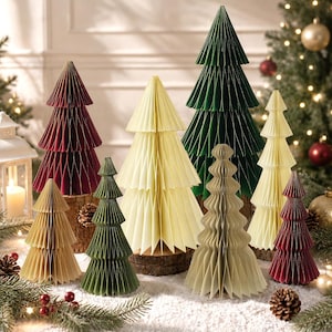 May include: A collection of decorative paper honeycomb Christmas trees in various sizes and colors, including dark green, cream, and deep red, each mounted on a small circular wooden base with pleated paper layers.