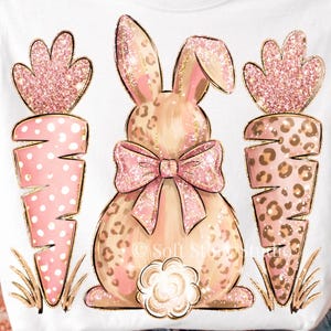 May include: A pink and gold Easter-themed graphic featuring a bunny with a bow and two carrots. The bunny has a leopard print pattern, and the carrots have a polka dot design. The image is embellished with glitter accents.