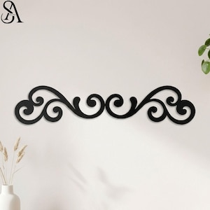 May include: Black metal wall decor featuring a symmetrical, swirling scroll design. The decorative piece has a series of curved lines and circular elements, creating an elegant, flowing pattern. This wall art is designed to be mounted horizontally.