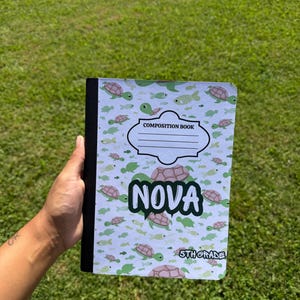 Può includere: Un quaderno di composizione con copertina bianca caratterizzato da un motivo ripetuto di piccole tartarughe e pesci verdi e rosa. Al centro un'etichetta con il testo COMPOSITION BOOK, il nome NOVA e 5TH GRADE nell'angolo.
