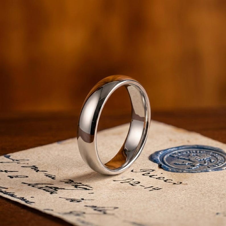 May include: A polished silver-toned metal ring with a smooth, rounded exterior surface and a warm, light brown wood grain inlay visible on the inner band, reflecting light across its curved, metallic finish.