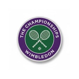 May include: A circular patch featuring the Wimbledon Championships logo. The design includes two crossed tennis rackets, a tennis ball, and the words "THE CHAMPIONSHIPS WIMBLEDON" in white text on a purple and green background.