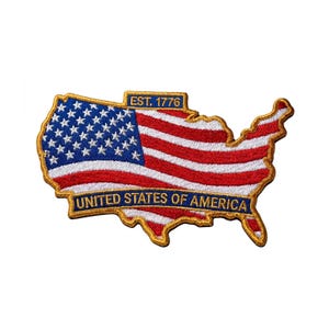 May include: Embroidered patch in the shape of the United States, featuring the American flag design. The patch includes the text "EST. 1776" and "UNITED STATES OF AMERICA" in a gold border.