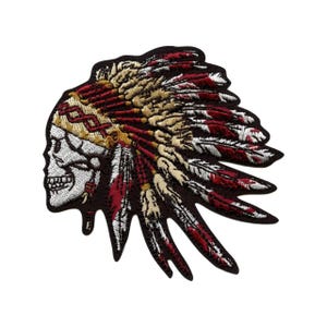 May include: Embroidered patch featuring a skull wearing a Native American headdress. The patch has a dark brown border, with the headdress in shades of red, tan, and black. The skull is white with black details, and the feathers are detailed.