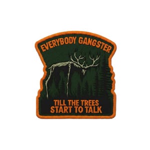 Może przedstawiać: Haftowana naszywka z pomarańczową obwódką i napisem "EVERYBODY GANGSTER" oraz "TILL THE TREES START TO TALK". Naszywka przedstawia sylwetkę jelenia na tle leśnej scenerii, w kolorach zieleni i pomarańczy.