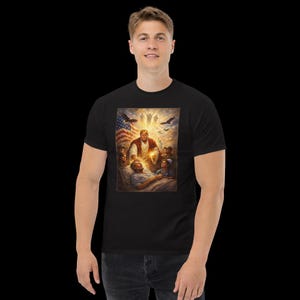 May include: Black t-shirt featuring a vibrant, detailed graphic. The artwork depicts a figure in a red robe with a glowing aura, surrounded by others, with an American flag and eagles in the background. The design has a religious theme.
