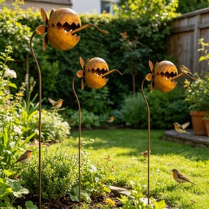 May include: Three rusty metal garden ornaments shaped like flowers with open, jagged mouths. Small birds perch on the ornaments and in the surrounding green grass and bushes. The ornaments are on tall, thin stems.