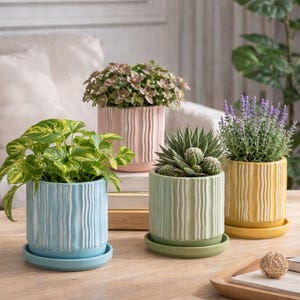 May include: A set of three ceramic mugs with a speckled, matte finish. The mugs are in shades of cream, light grey, and dark grey. Each mug has a simple, minimalist design, ideal for coffee or tea.